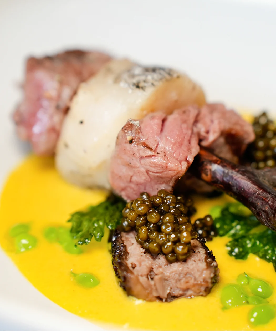 Carre d'agnello con caviale premium su crema gialla, piatto fine dining