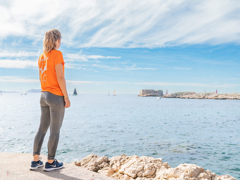 Femme en orange qui se tient debout face à la mer de Marseille lors d'un week-end entre copines dans la cité phocéenne