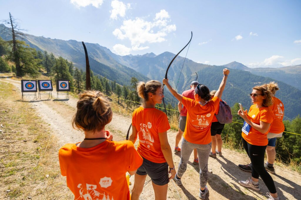 Femme qui lève les bras en signe de victoire après avoir tiré à l'arc et entourée d'autres femmes lors d'une visite de Samoëns