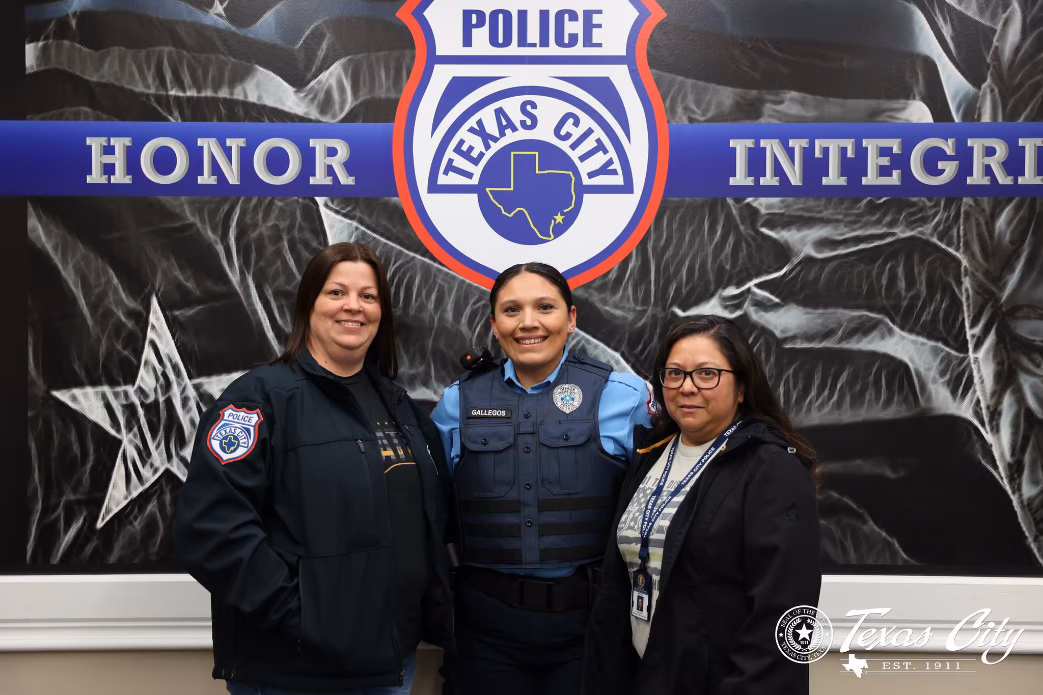 Three women standing in front of Texas City Police emblem with words Honor and Integrity behind them.