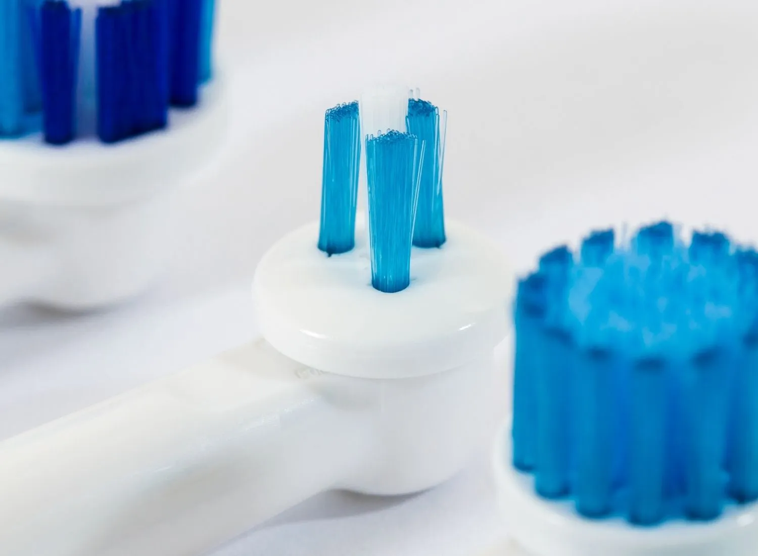 Close-up of white electric toothbrush heads with blue bristles on a white background.