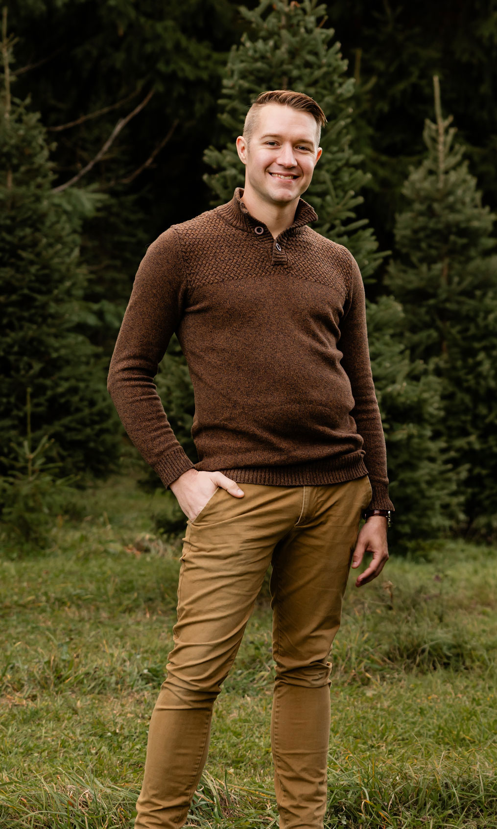 Photo of Jonathan standing in front of a pine tree forest.