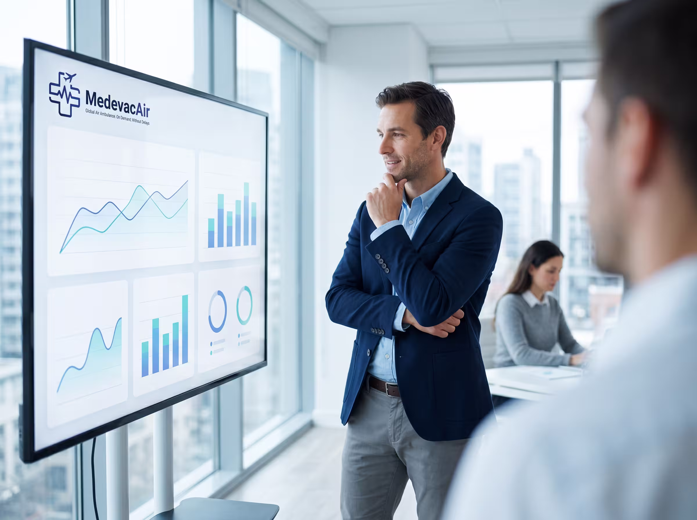 Businessman in a suit looking at data charts on a large screen in a modern office.