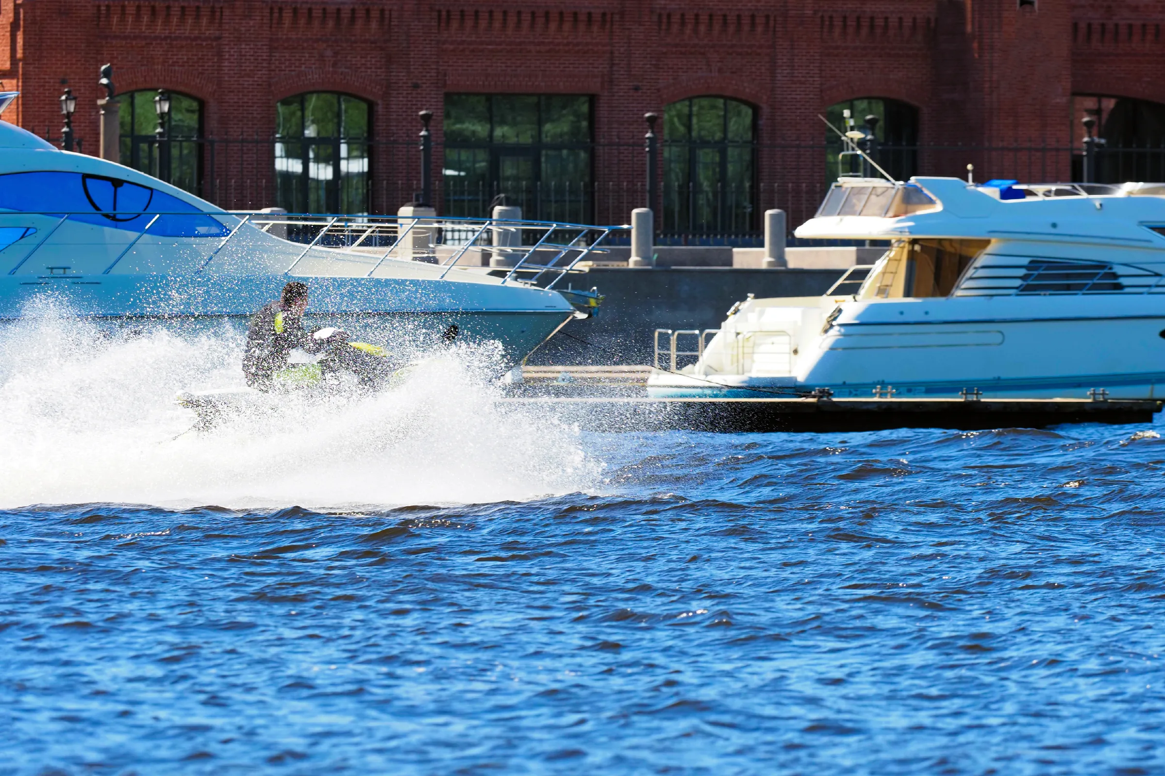 Personal watercraft at speed in front of docked yachts