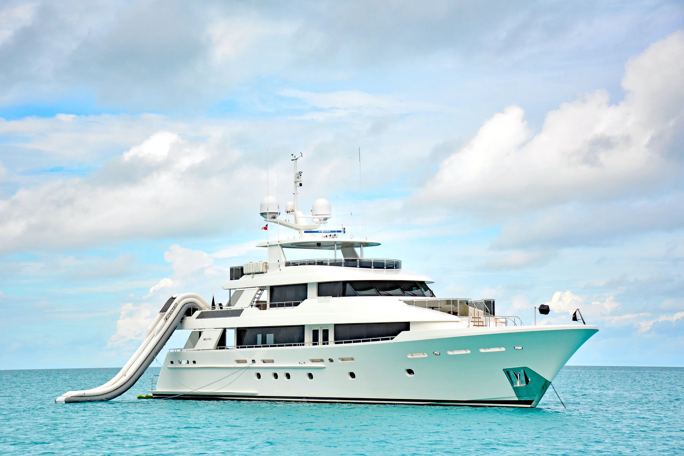 Charter yacht at anchor with its inflatable slide deployed from the upper deck
