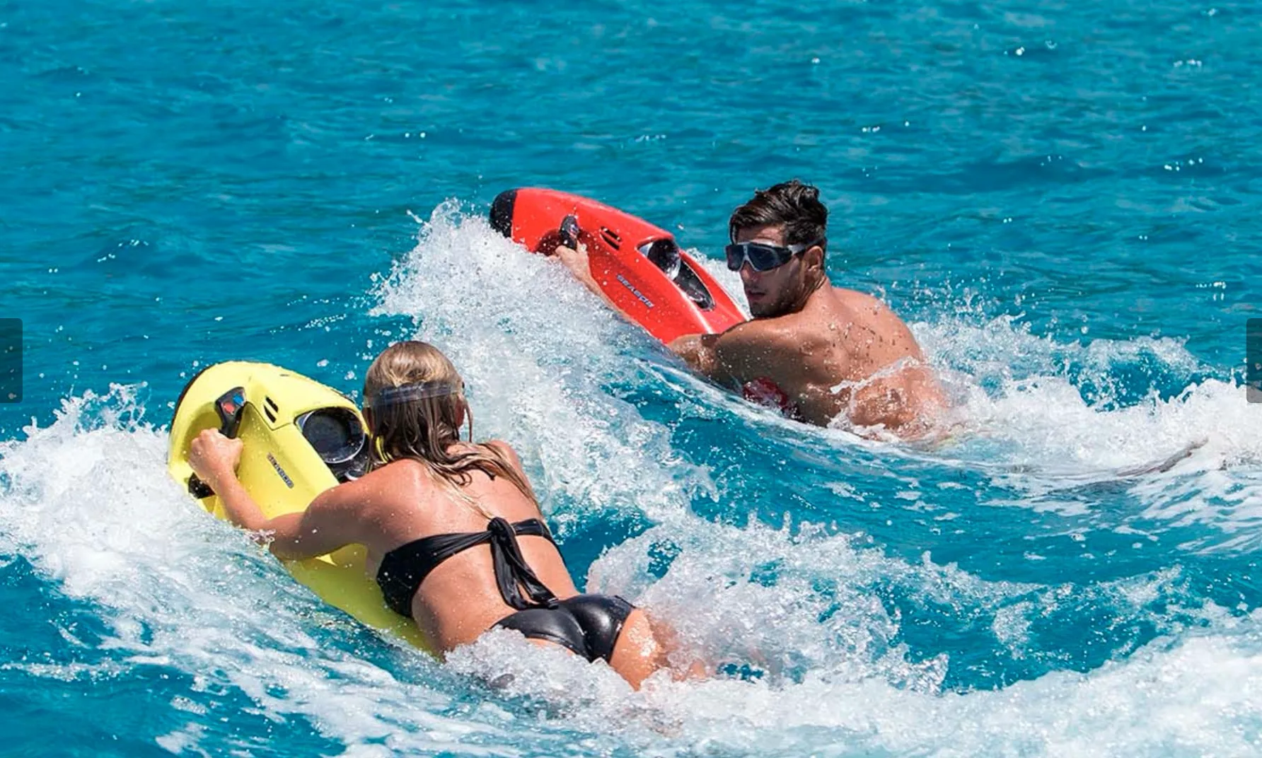 Two riders on SEABOBs cutting through clear blue water