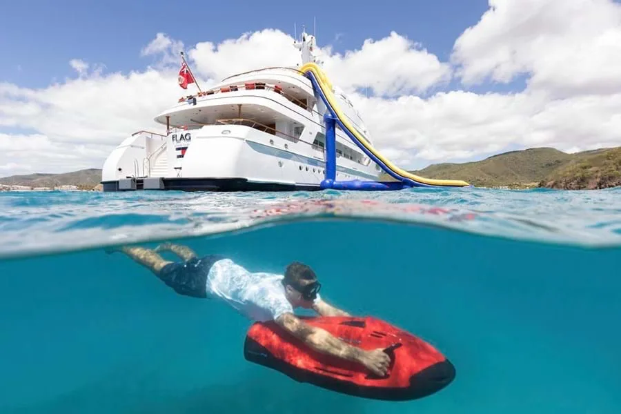 Yacht at anchor with a slide rigged and a guest riding a SEABOB underwater