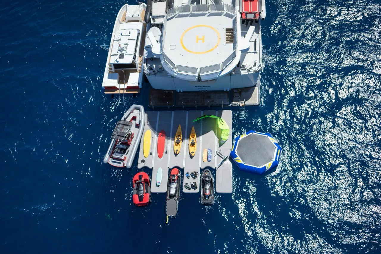 Superyacht from above with a full set of toys and inflatables off the stern