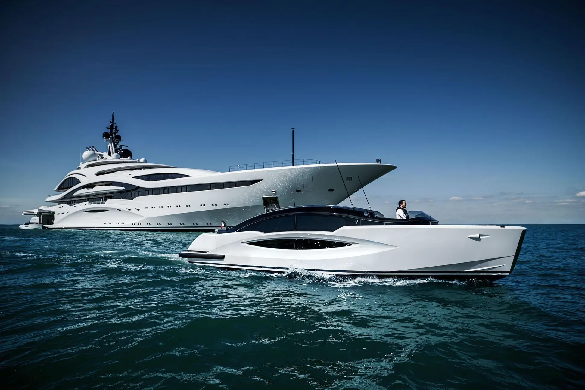 Superyacht at sea with its tender running alongside