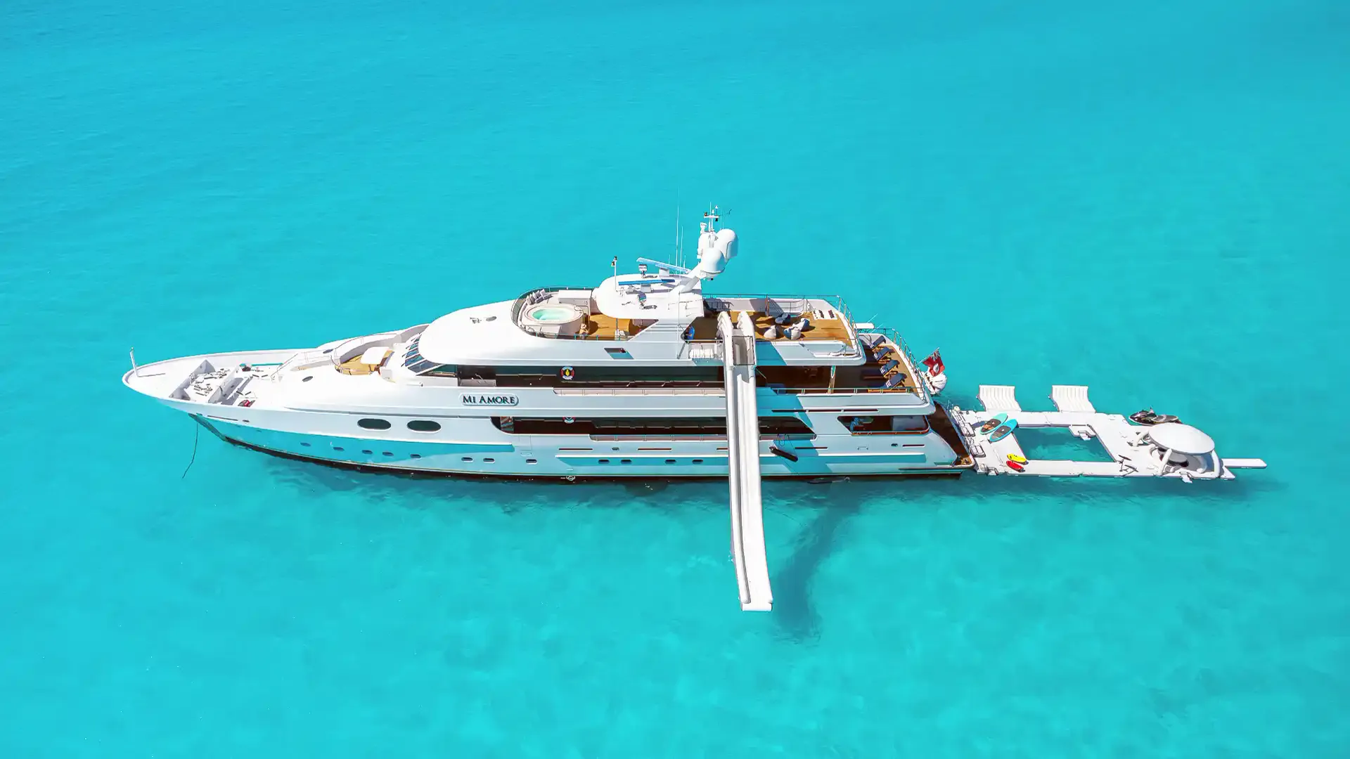 Superyacht with an AquaBanas slide from the upper deck, plus a floating dock and cabana off the stern