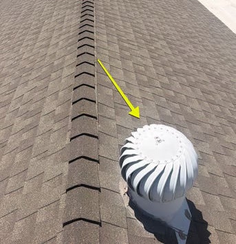 Shingle roof ridge with a white turbine (whirlybird) roof vent marked by a yellow arrow; the inspector flagged this vent for replacement.