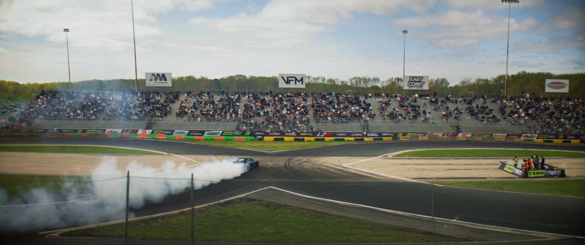 Drift cars mid-corner with crowd along the fence