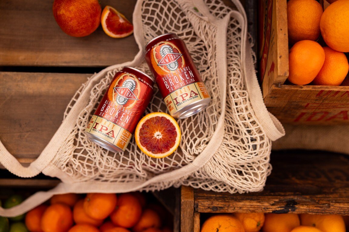 Blood Orange Broken Heels cans in a market bag flat lay