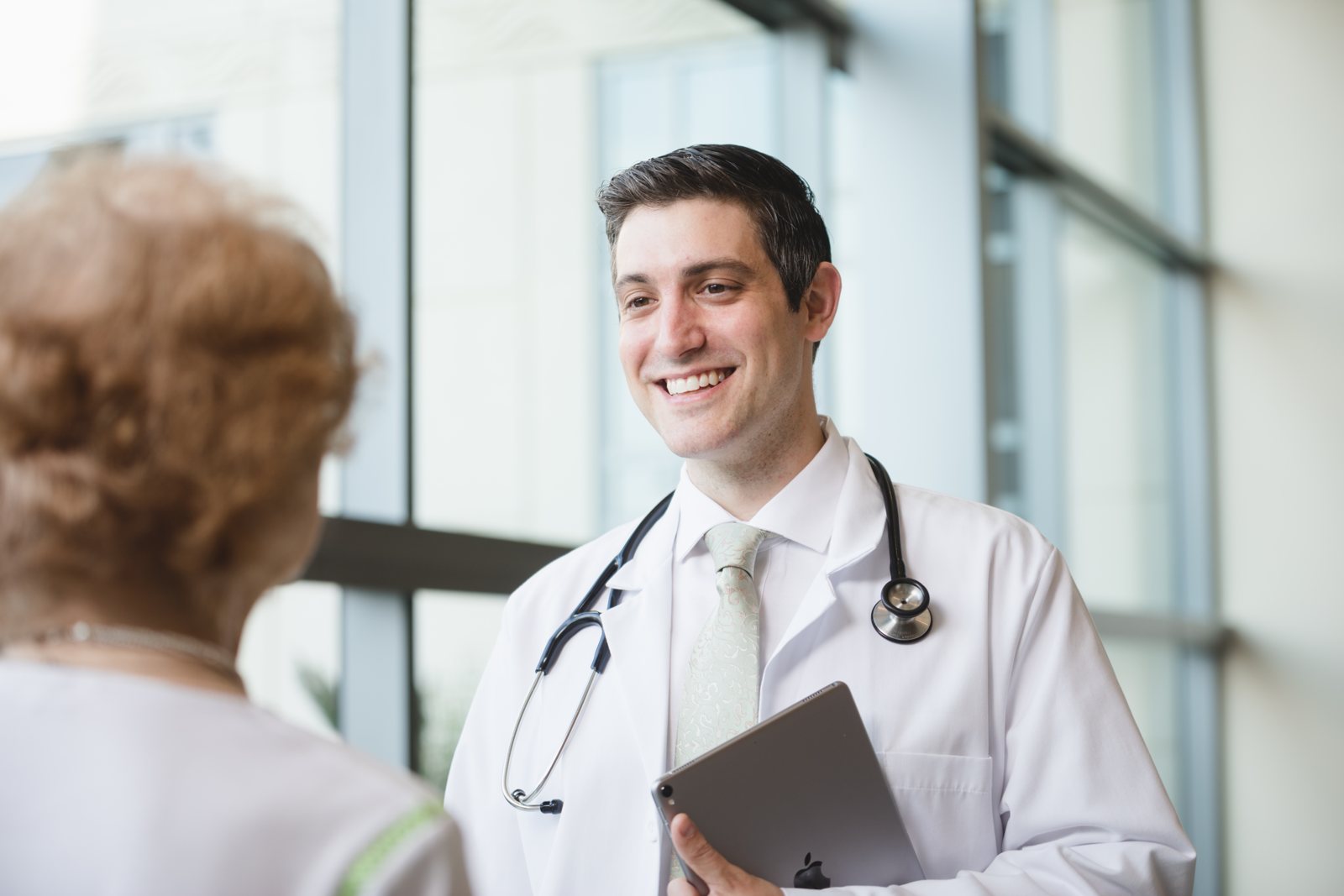 UPMC physician in a white coat talking with a patient by a window