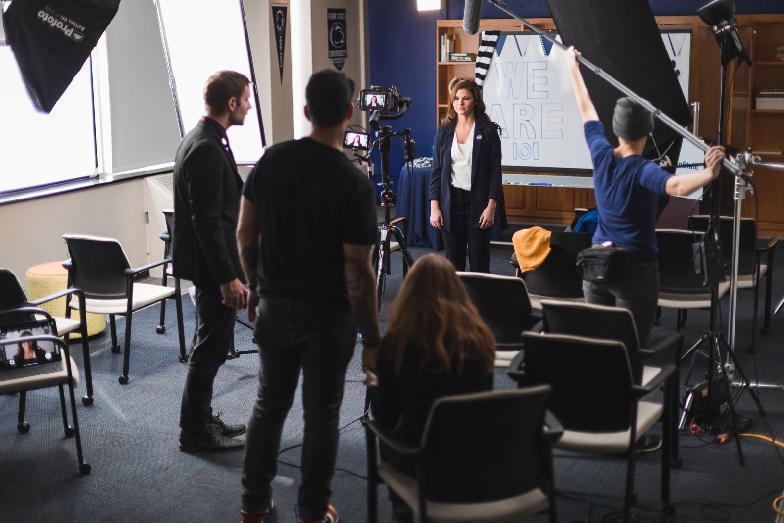 Crew lighting the classroom set with the host at the board
