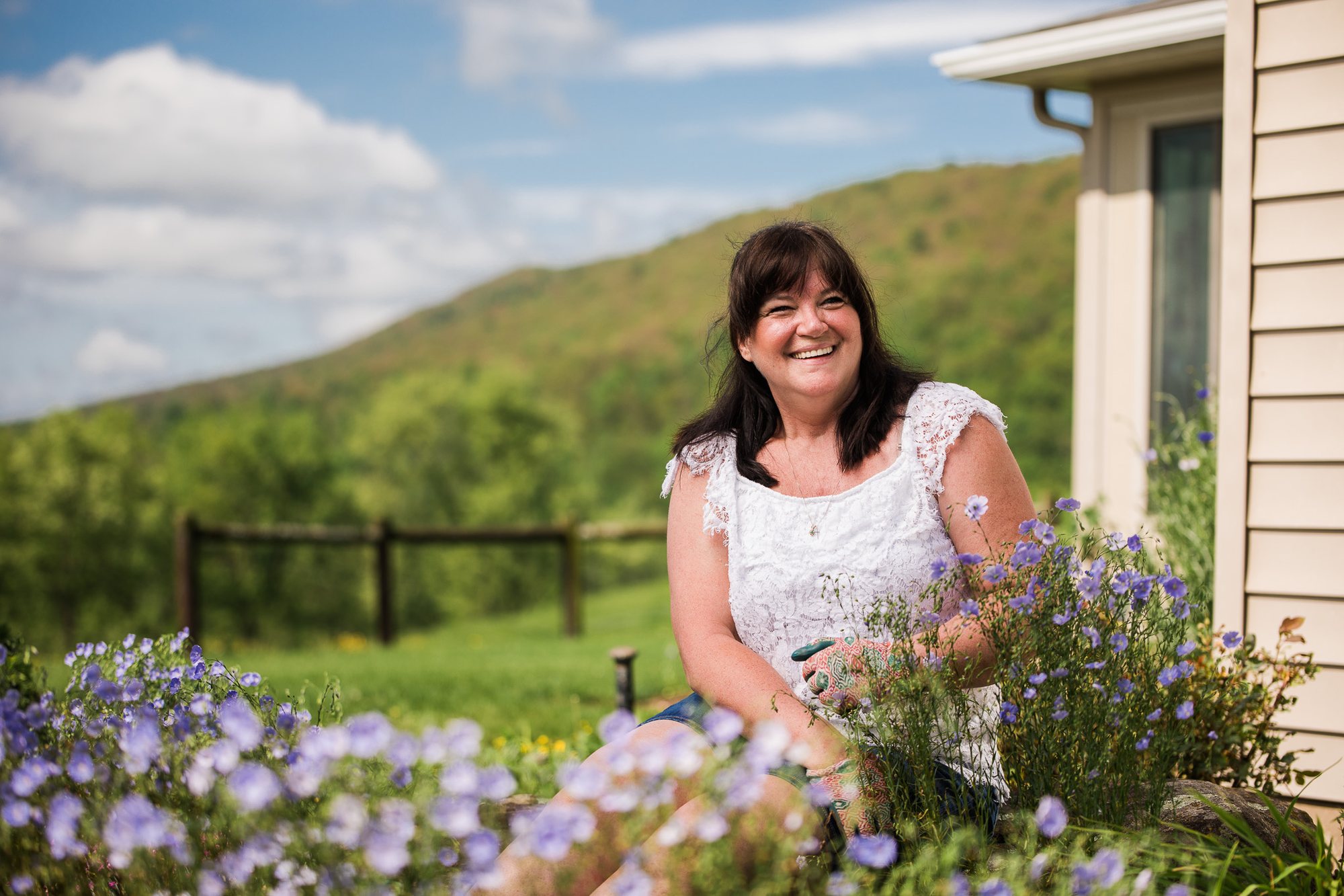 UPMC patient story portrait, a woman smiling among flowers outside her home