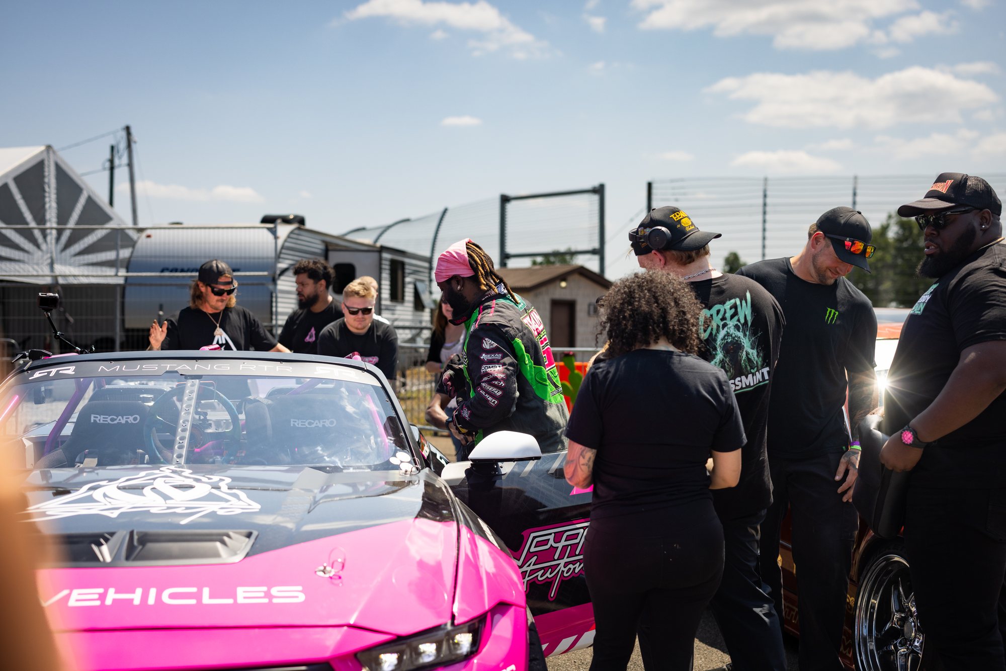 Drift team gathered around a pink car in the GRIDLIFE paddock