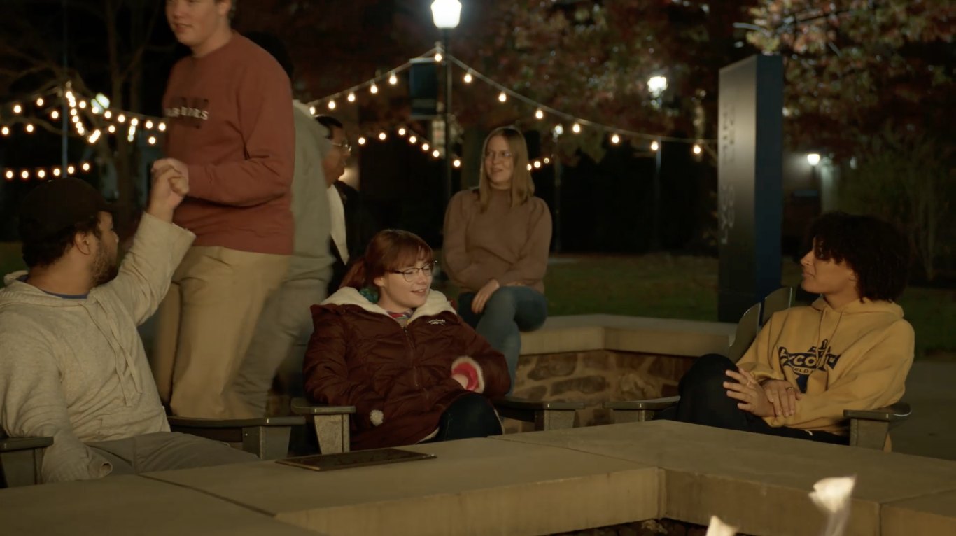Students gathered around the fire pit on campus after dark