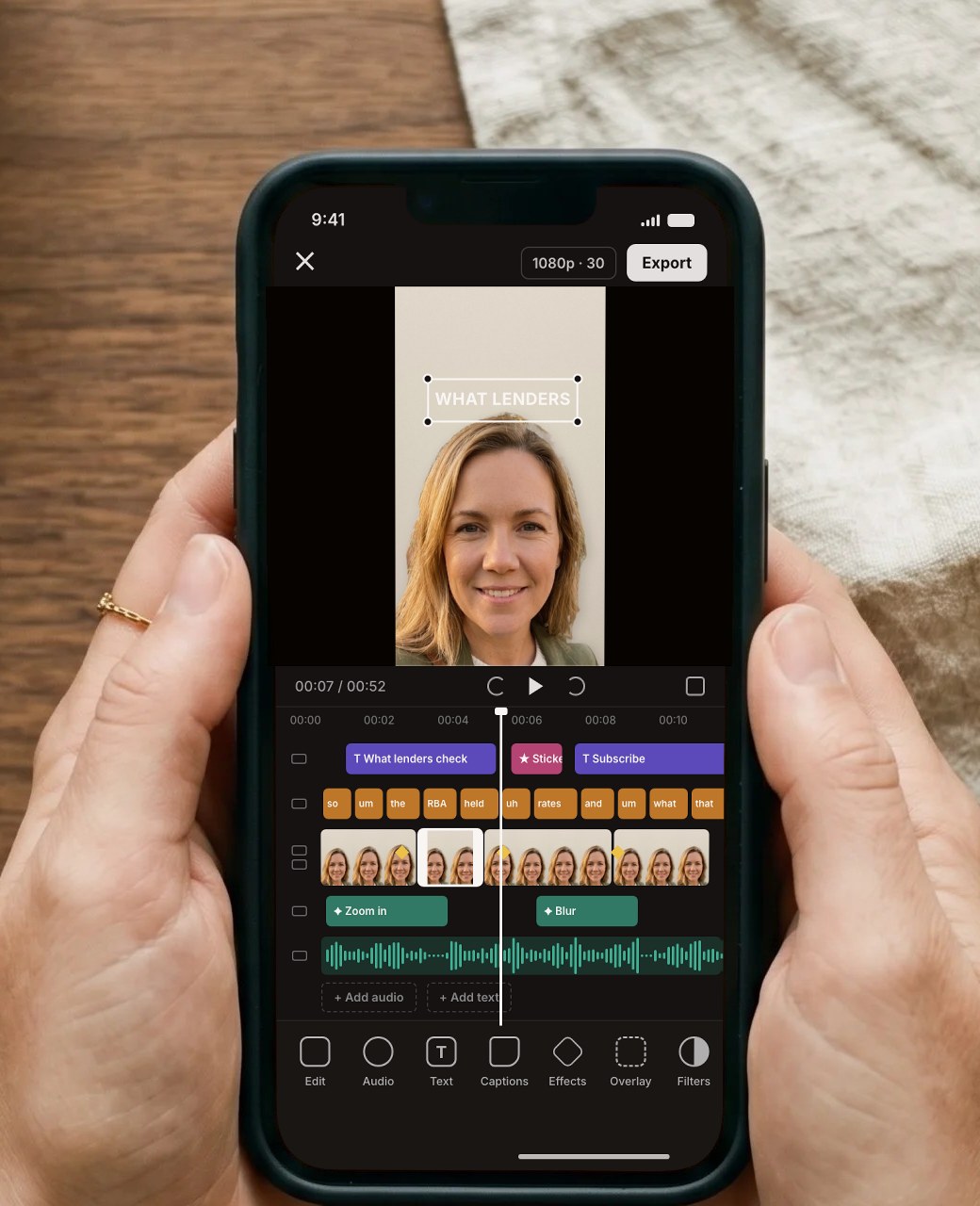 The same hands holding a phone showing a crowded editing timeline