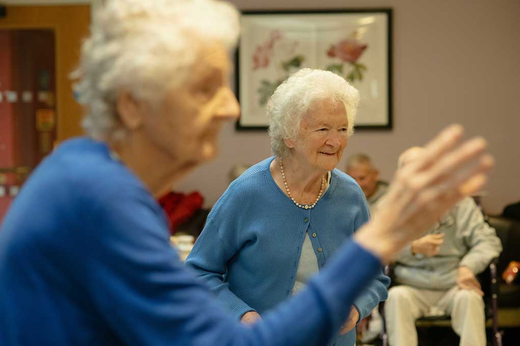 Two older women exercising together in a community setting