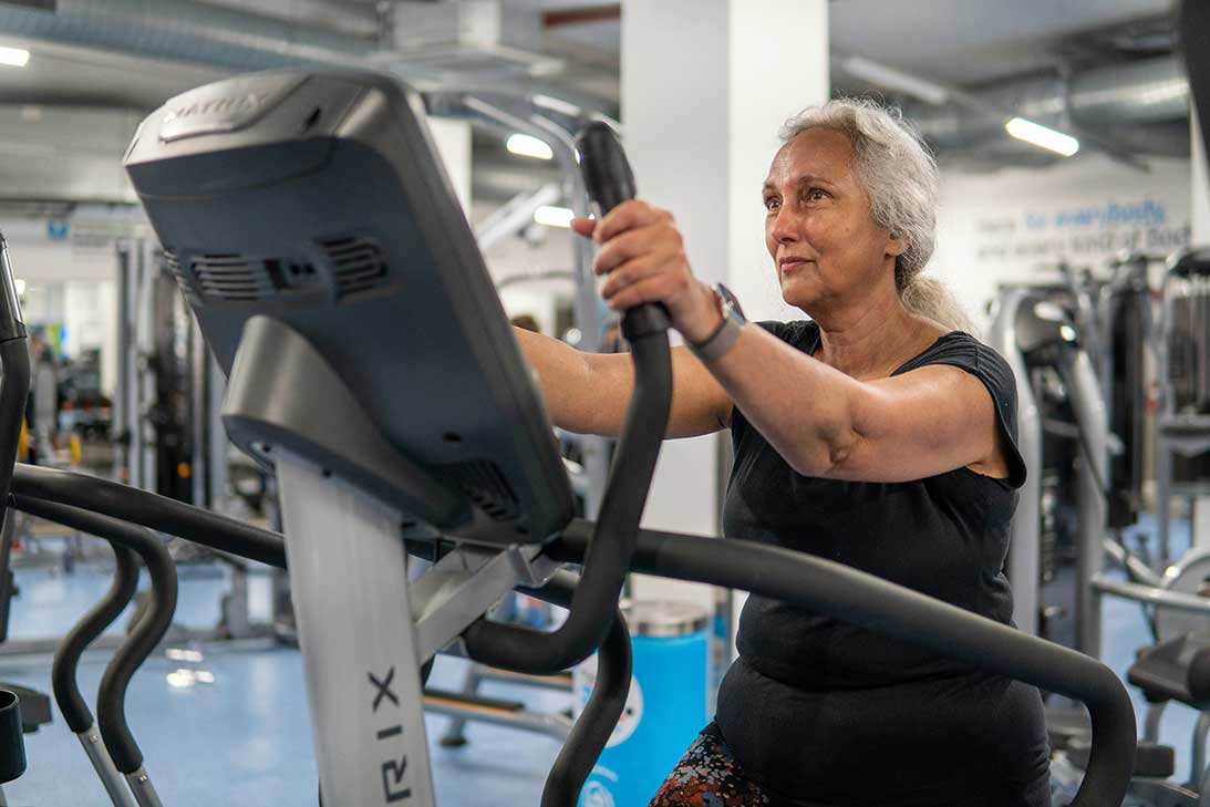 Older woman using an elliptical machine during a rehab session