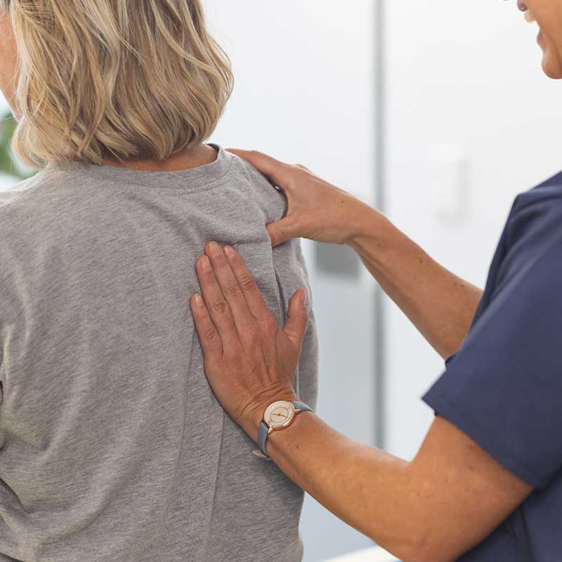 Physiotherapist assessing a patient's shoulder and upper back