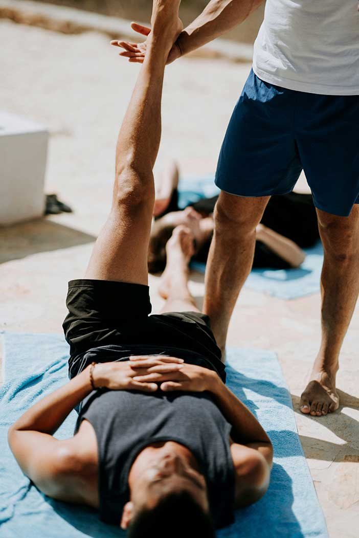 Group exercise class pair hamstring stretch in gym setting