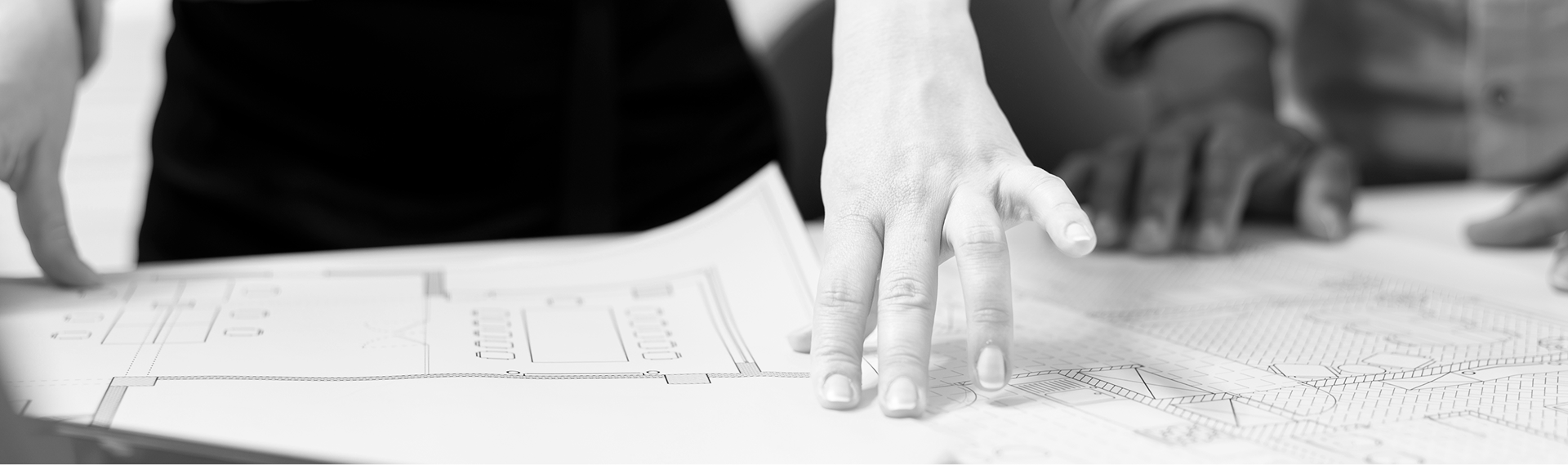 Mains d’une équipe examinant des plans d’architecture sur une table.
