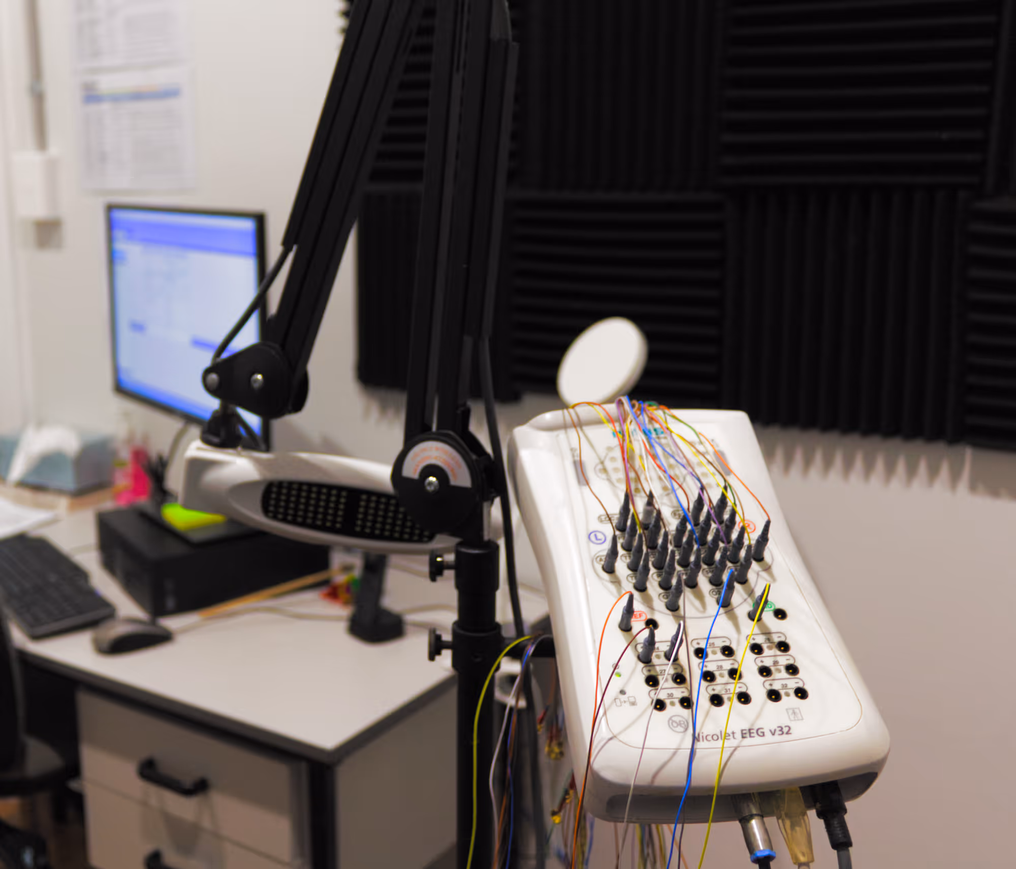 Nicolet EEG v32 machine with colorful wires connected, used for brainwave monitoring in a clinical room.