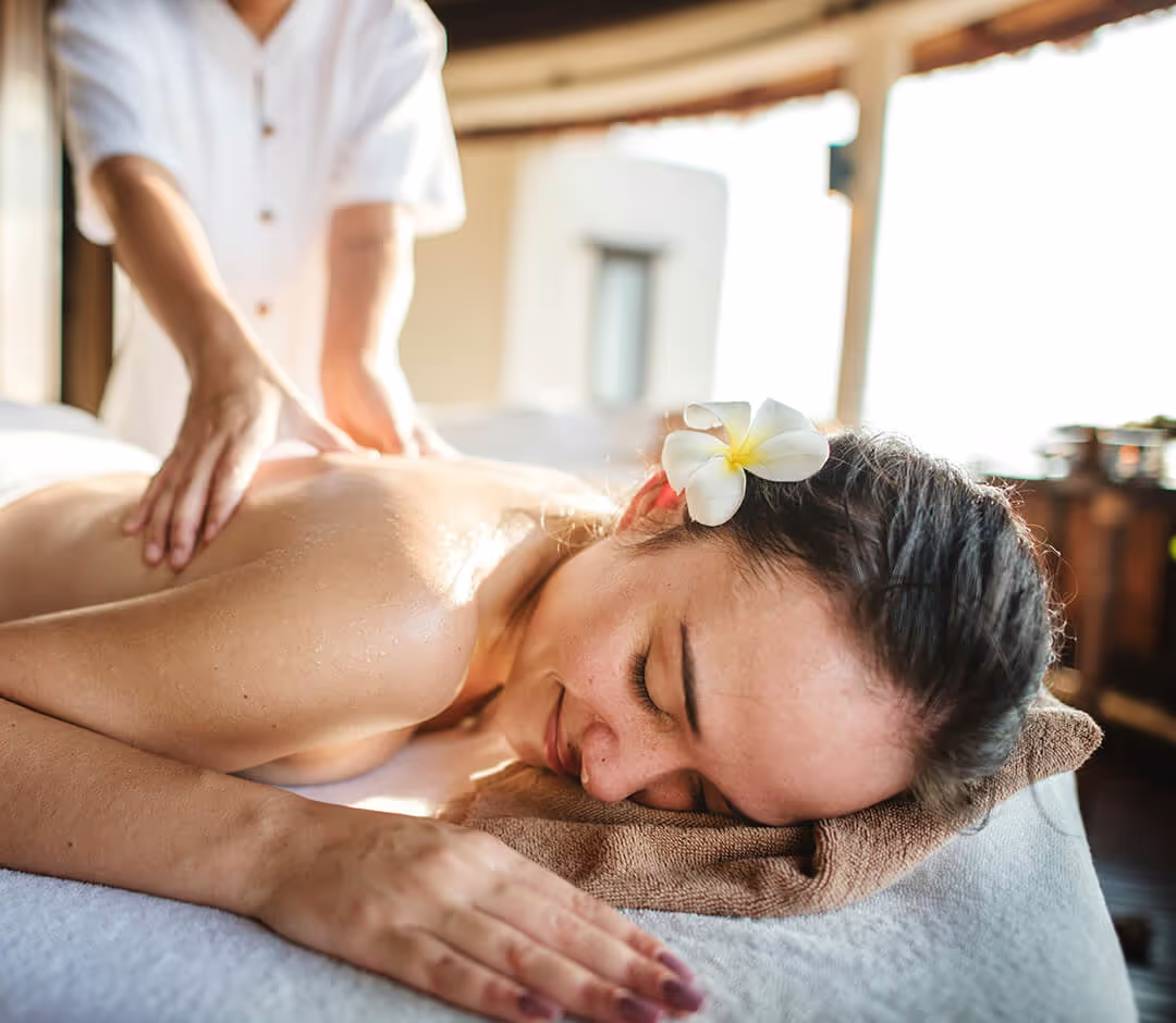 Close-up of hands giving a stomach massage to a person covered with brown towels.