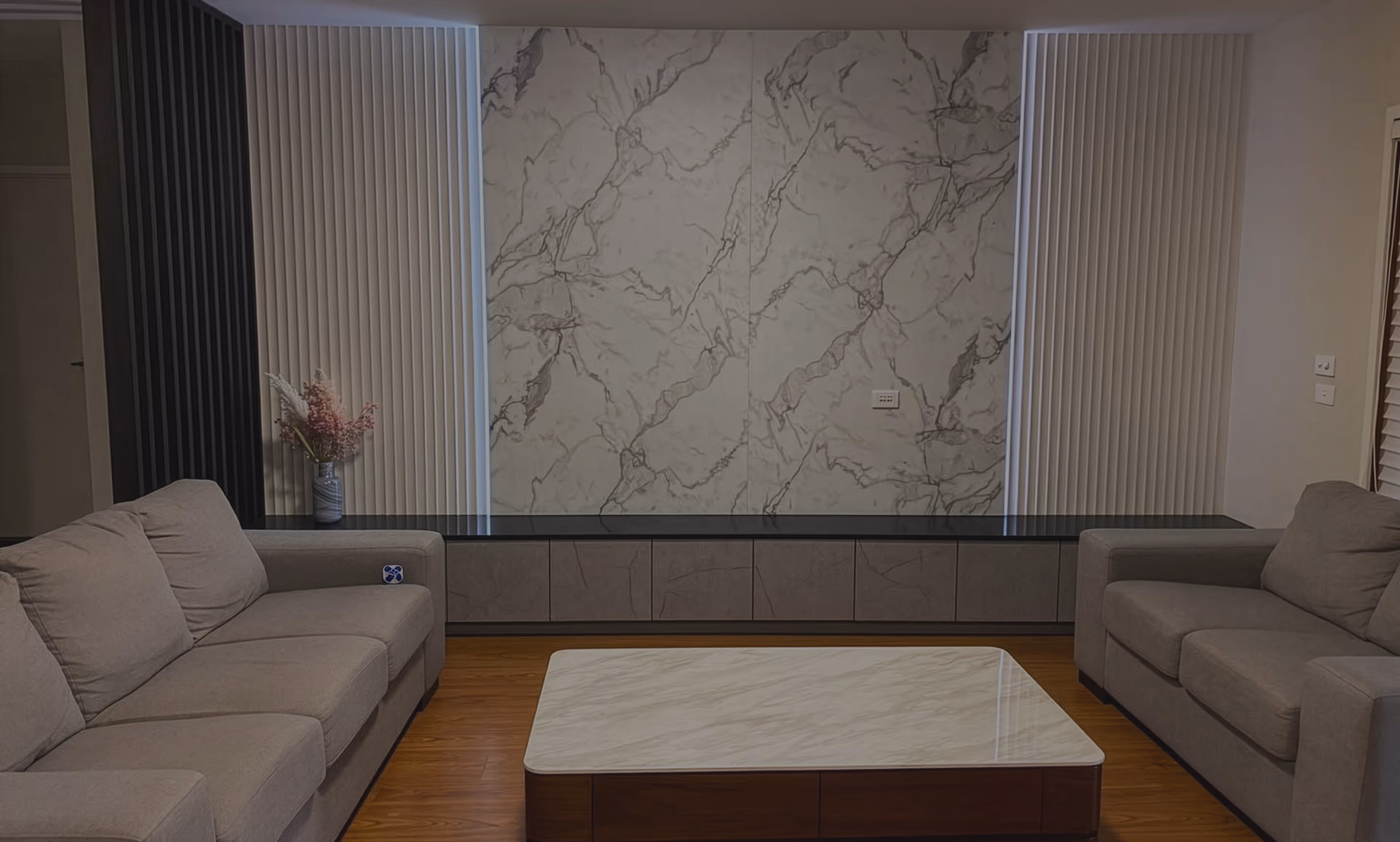 Modern living room with gray sofas, a white marble coffee table, and marble patterned wall panels.