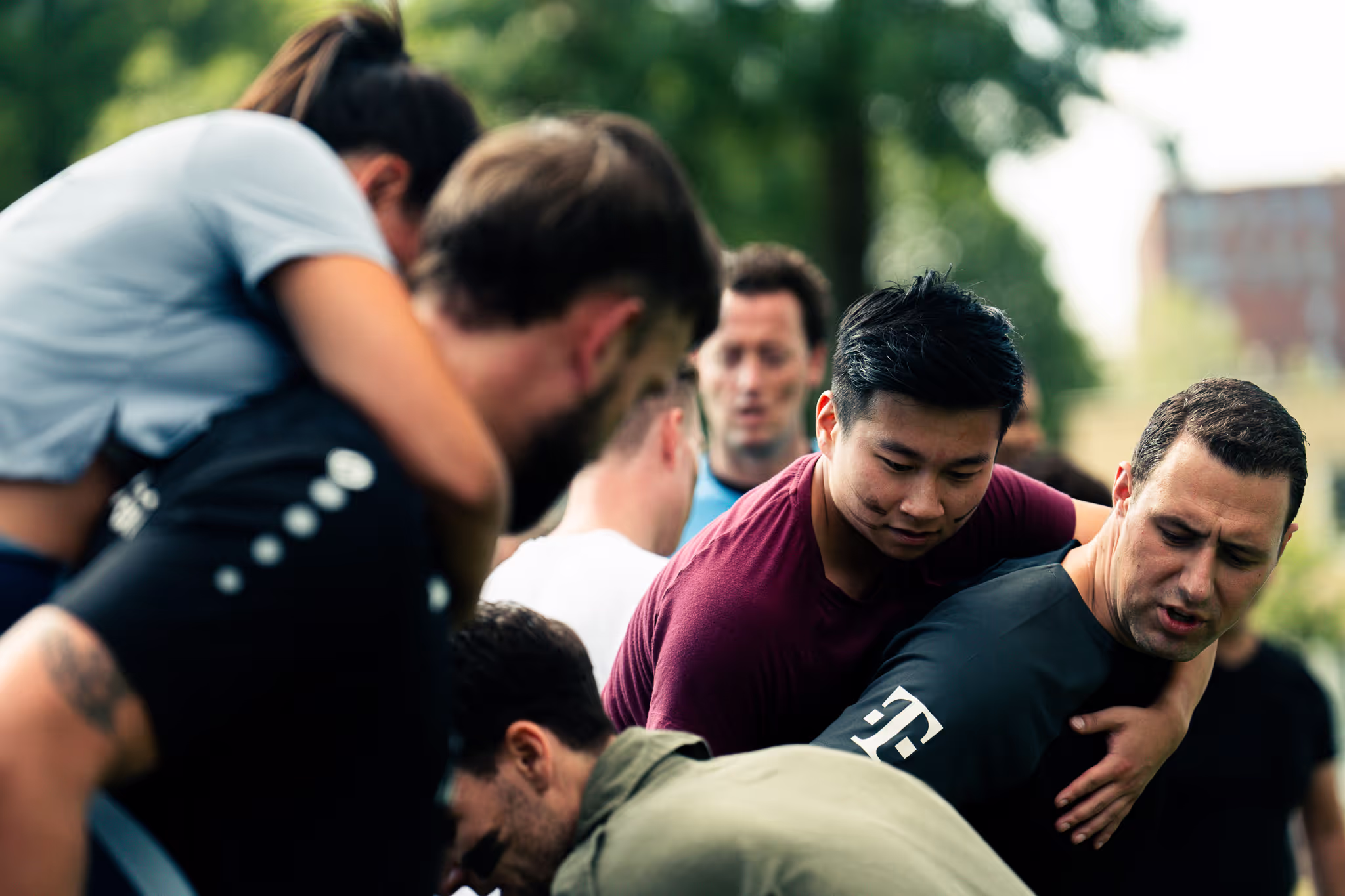 Groep mensen in een buitenomgeving die samenwerken en elkaar ondersteunen tijdens een fysieke activiteit.