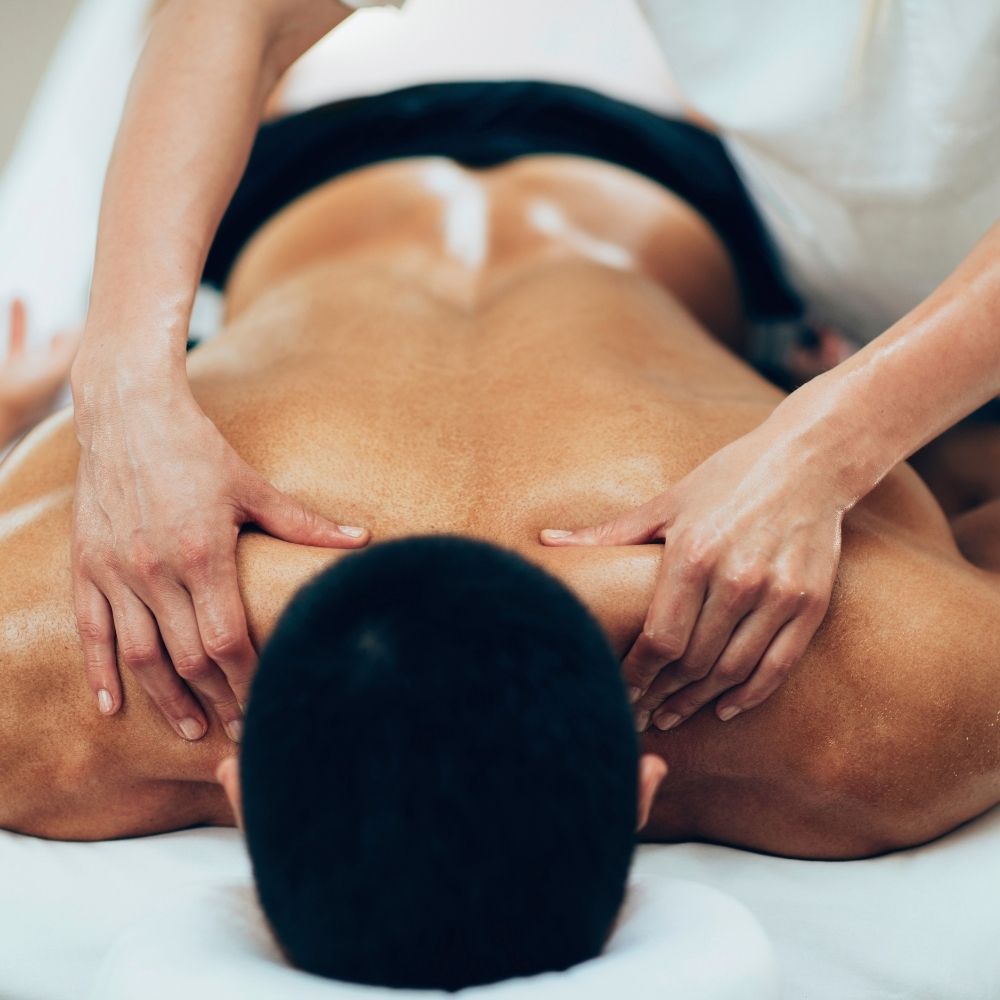 Person receiving a back massage while lying face down on a massage table.