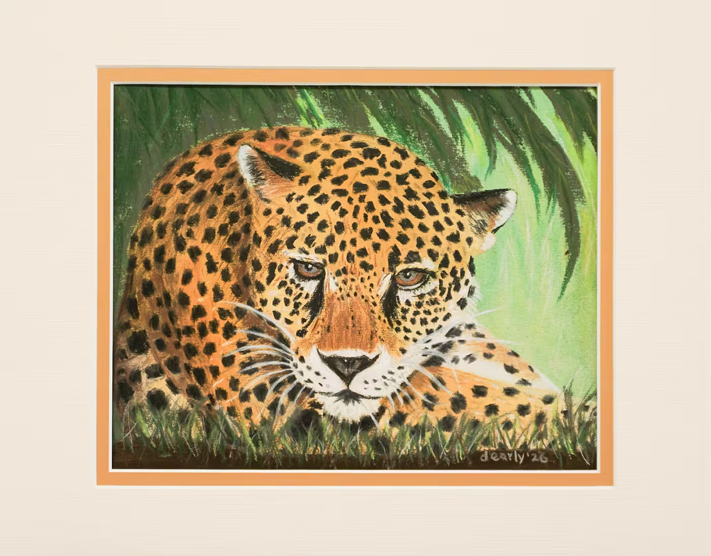 A leopard is lying down under green leaves, looking forward attentively.