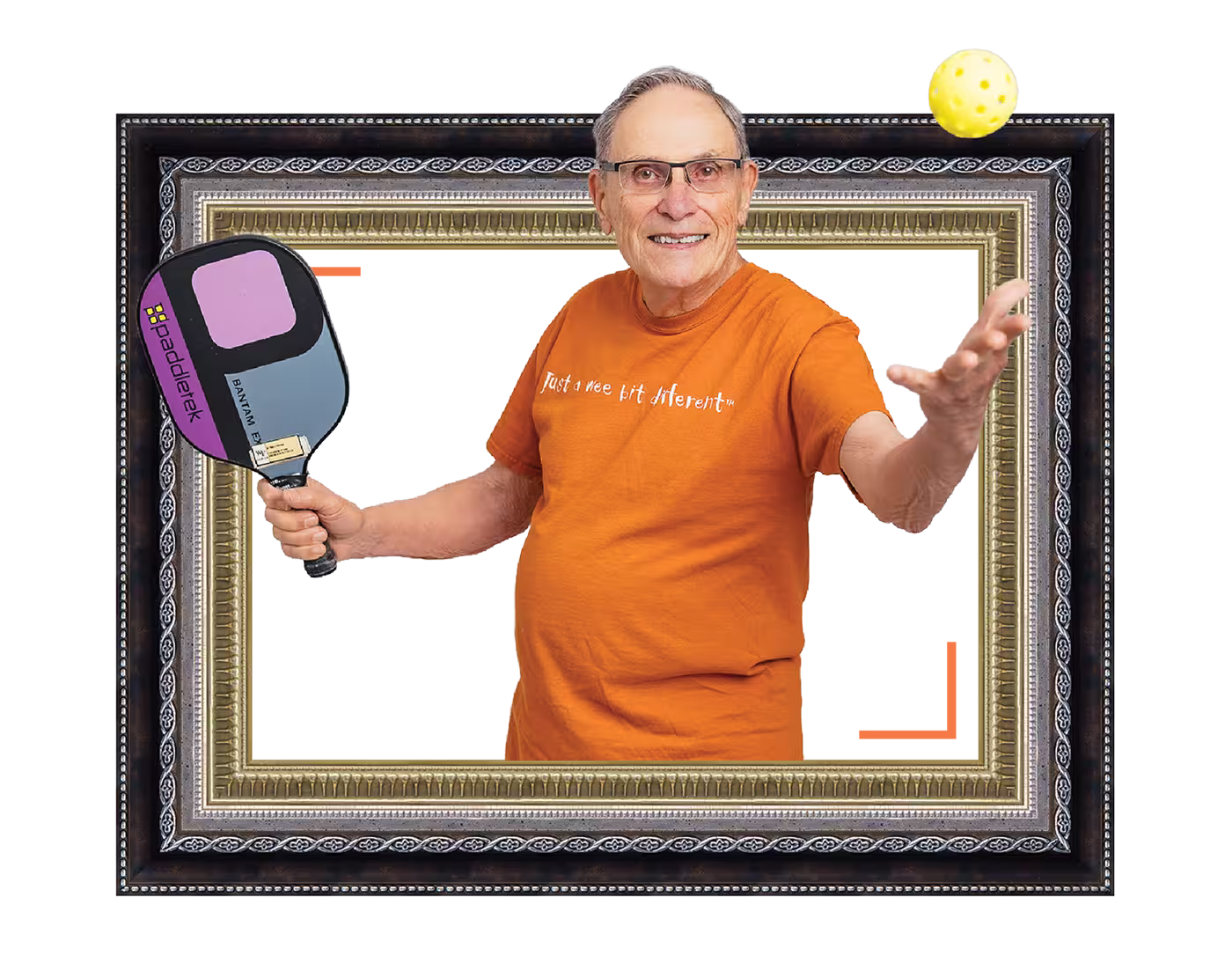 Man wearing an orange shirt plays pickleball, holding a paddle and reaching for a ball.