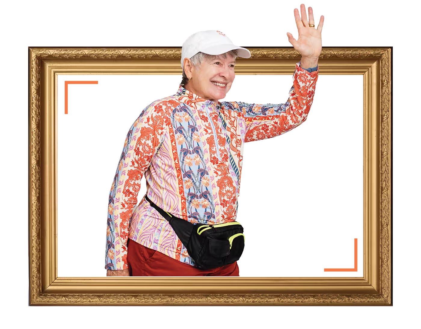Elderly person wearing colorful clothes and cap waves, standing in a picture frame with a smile.