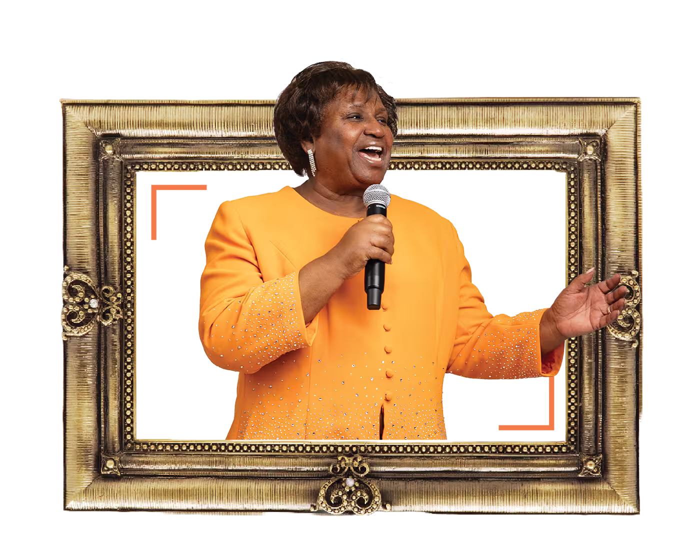 Woman in an orange outfit holding a microphone and smiling, standing inside a decorative frame.