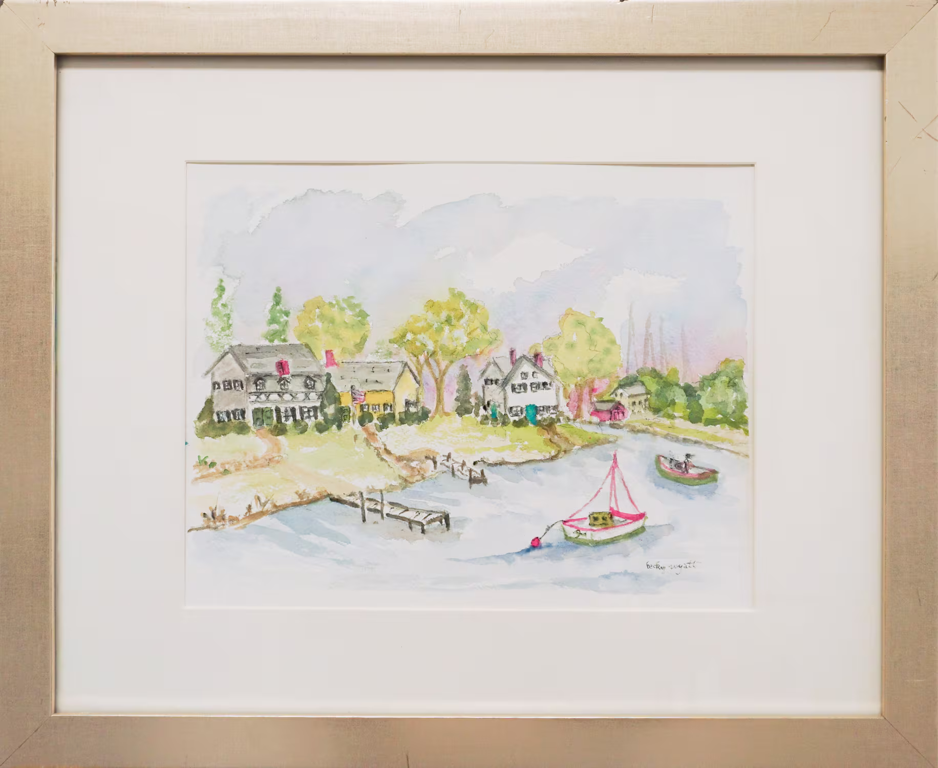A framed painting of a riverside scene with houses, a dock, and a boat on the water.