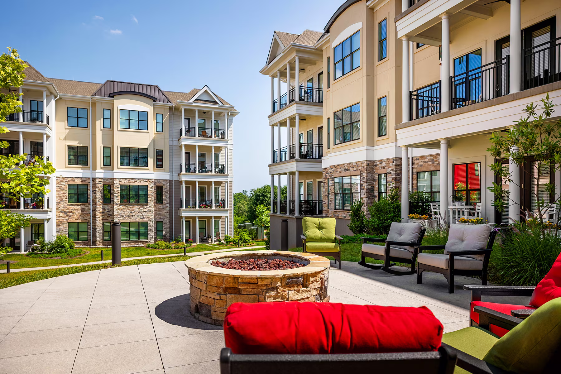 Outdoor patio area with a fire pit, surrounded by chairs and modern apartment buildings.