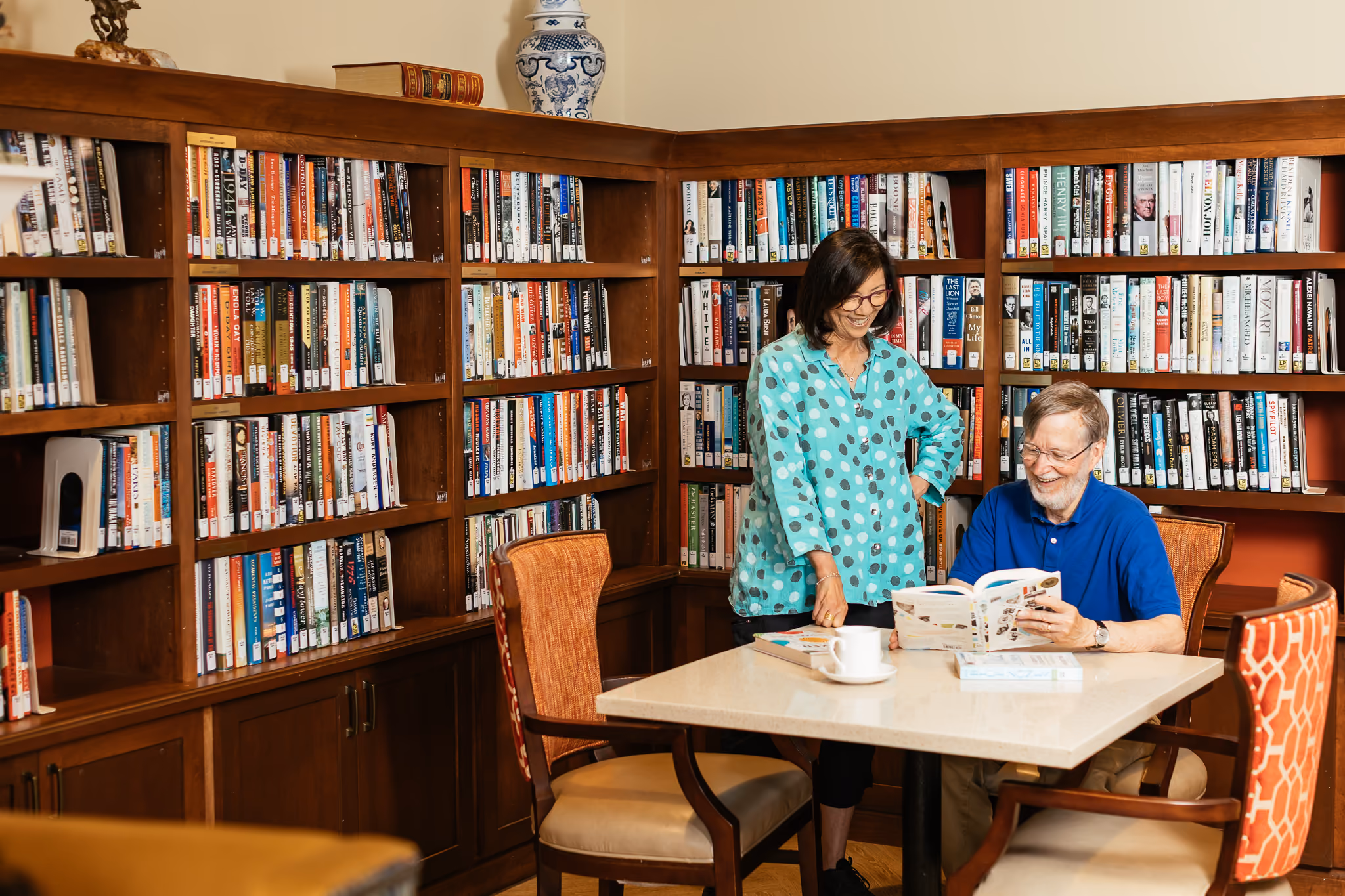 A woman and a man looking at a book together in a library setting.