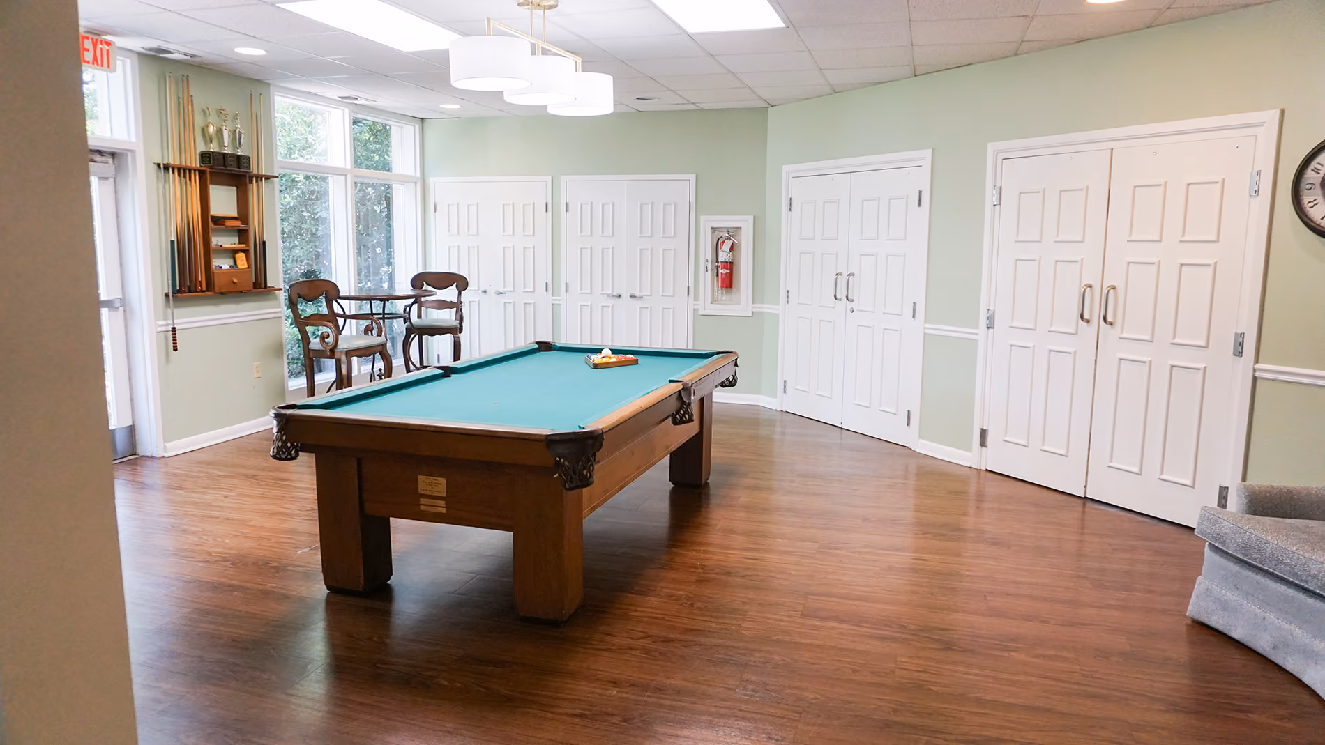 A pool table with a rack of balls is in the center of a recreation room.