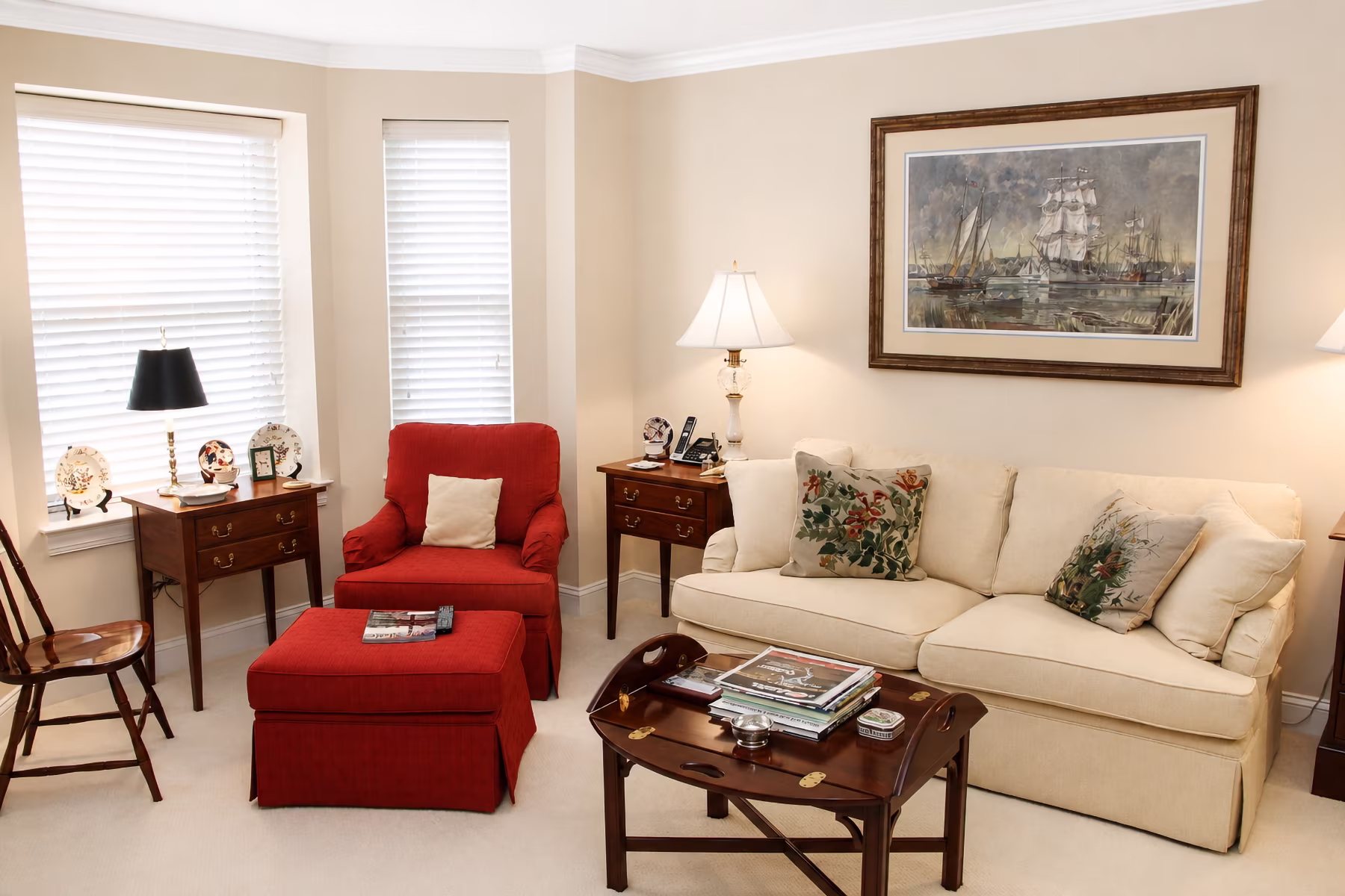 Living room with a beige sofa, red armchair, coffee table, and framed painting on the wall.