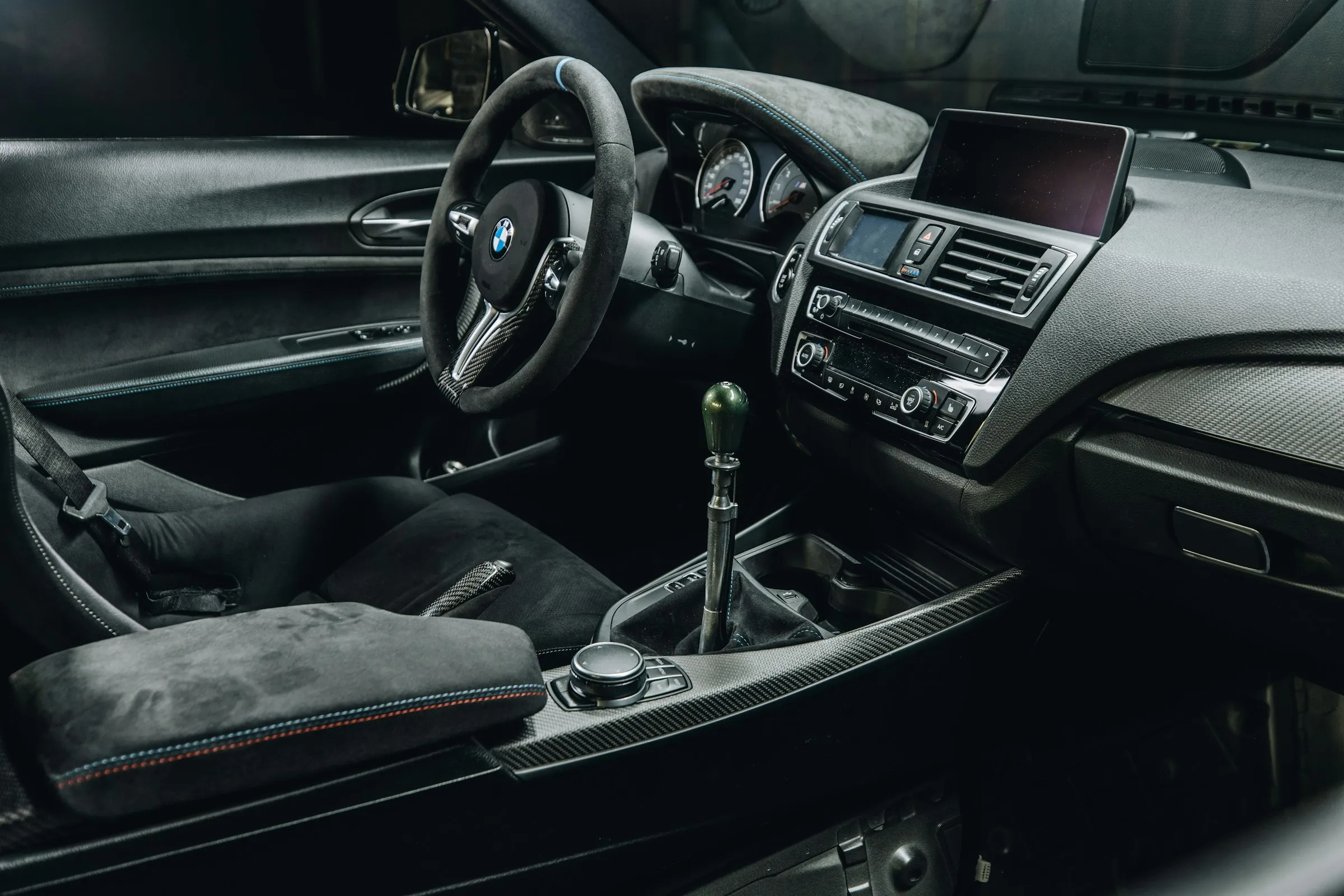 Interior of a BMW car featuring a steering wheel, manual gear shift, and center console controls.