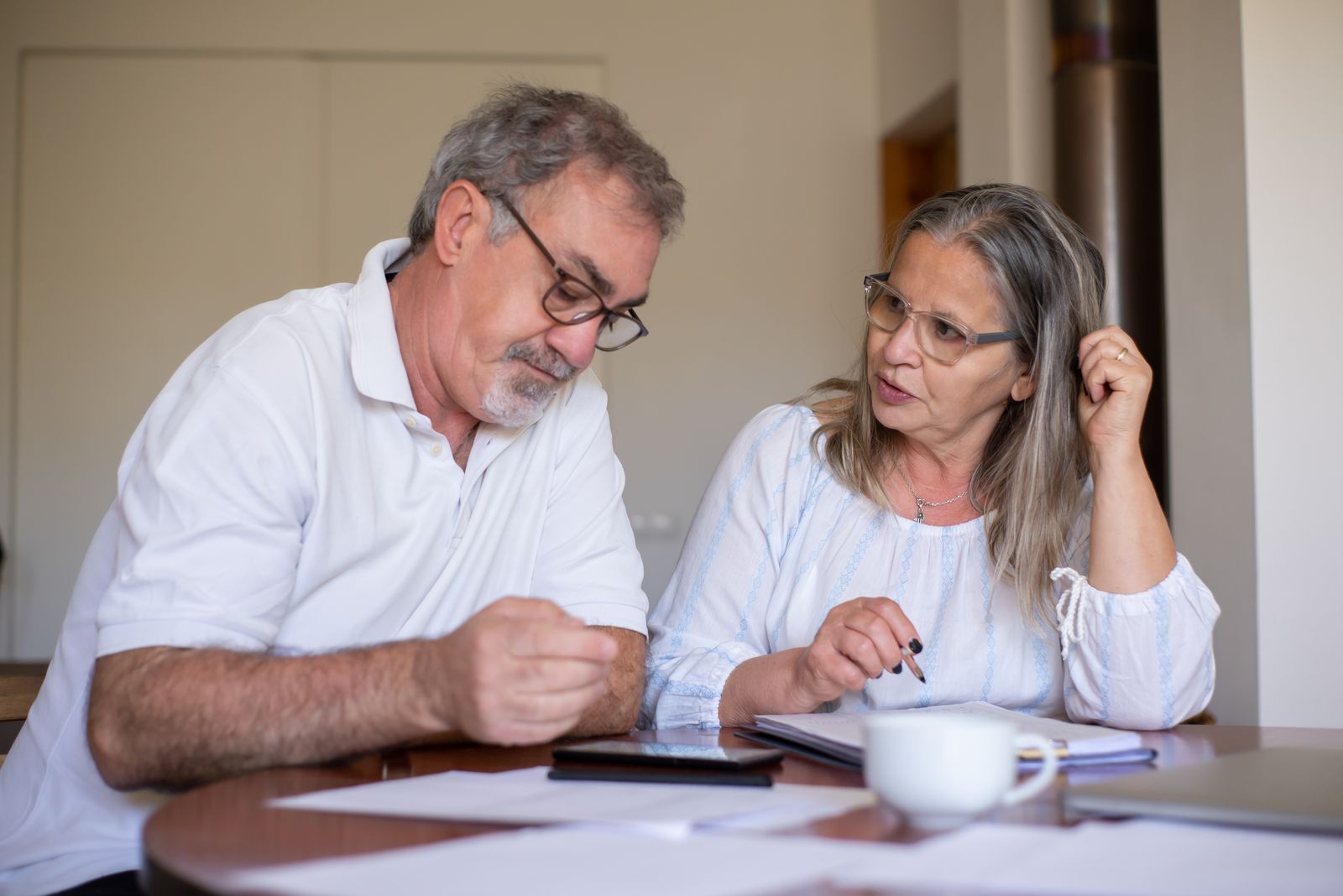 An older couple reviewing financial documents together at their kitchen table