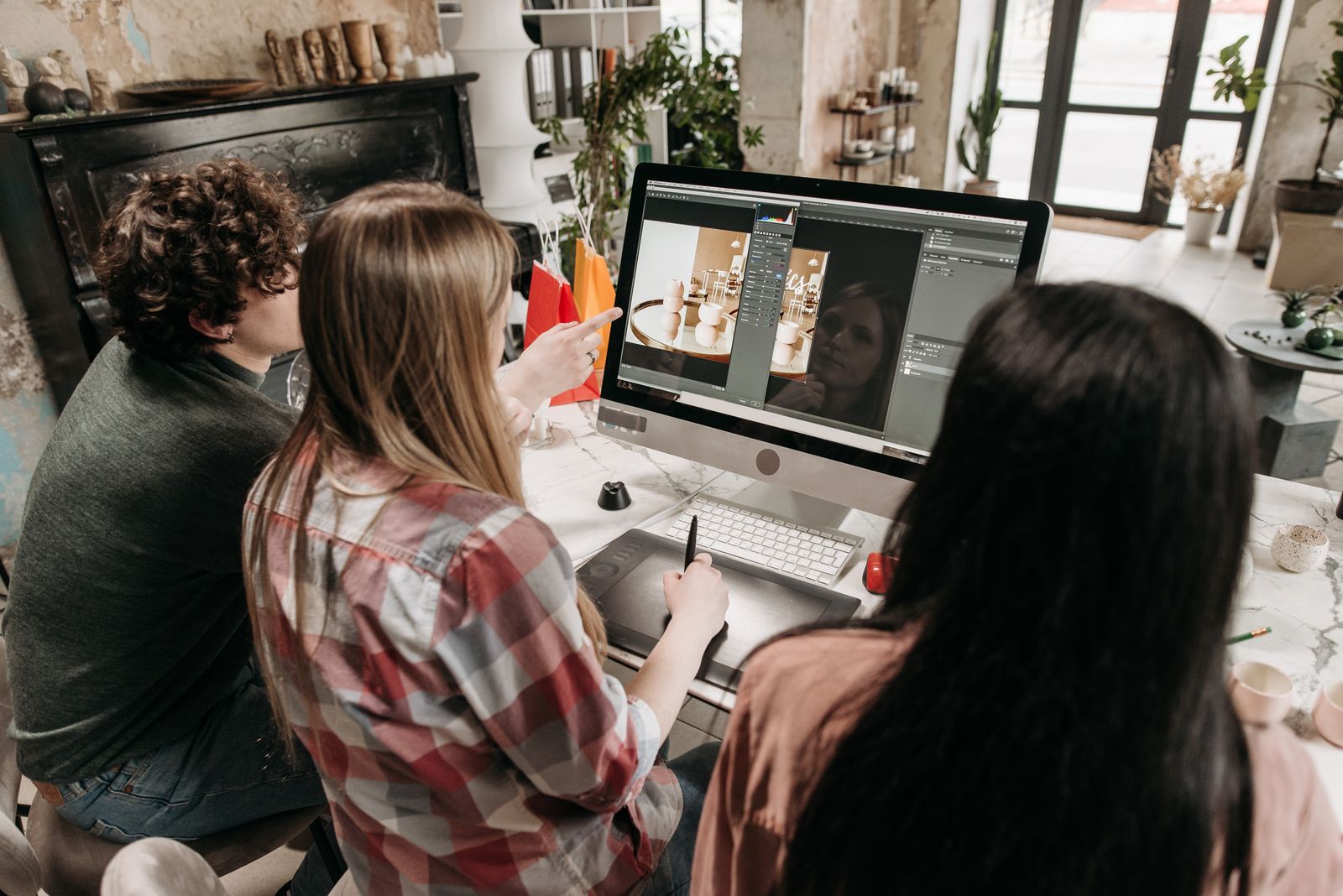 Group of young adults working on a design project at a desktop computer