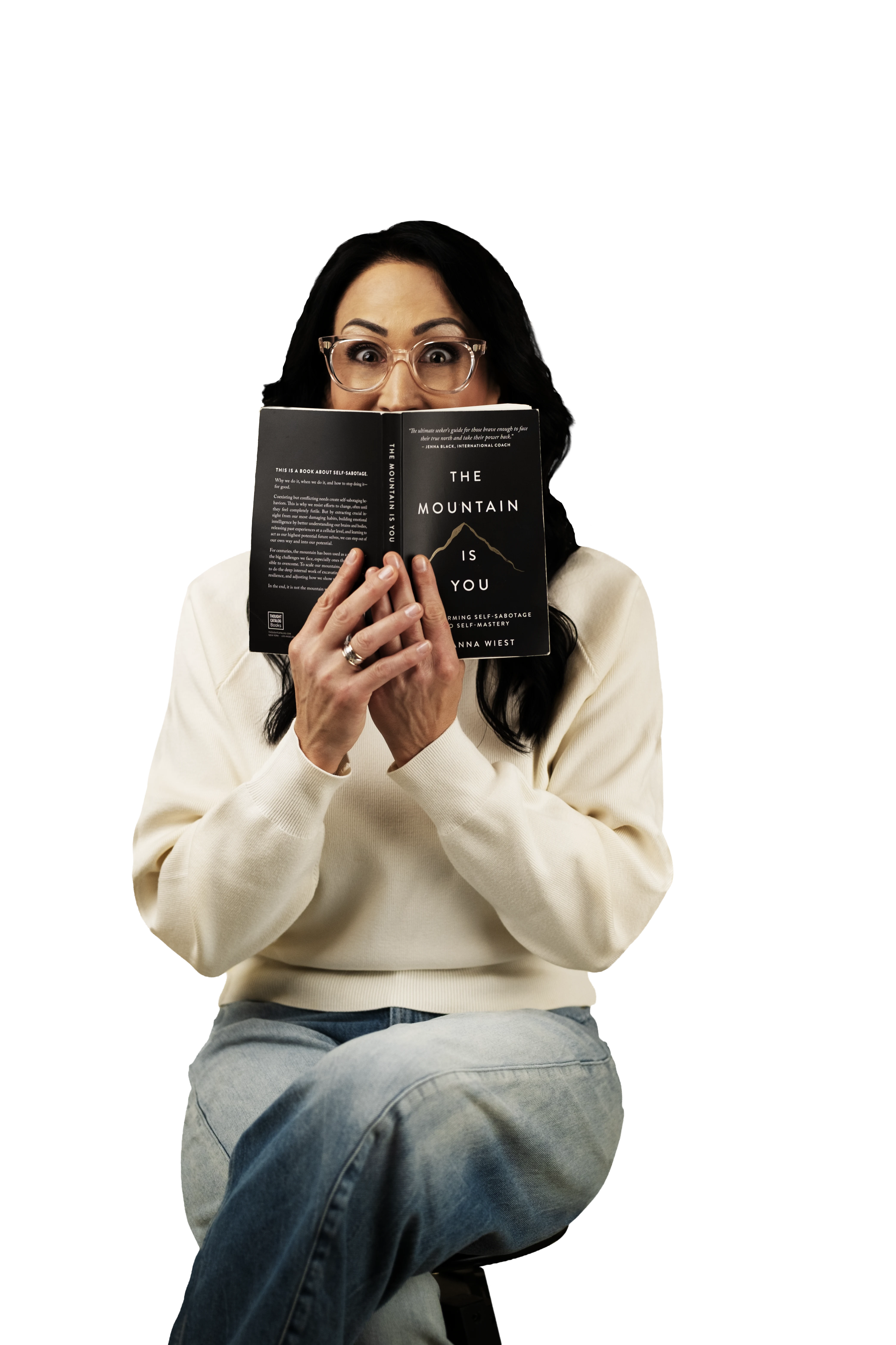 Woman with black hair and glasses peeking over a book titled The Mountain Is You.