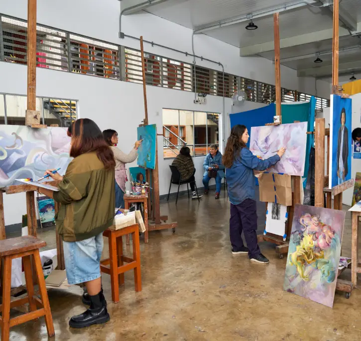 Alumnos pintando en caballetes en taller de arte