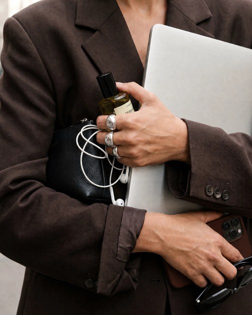 Person im braunen Blazer mit Laptop unter dem Arm