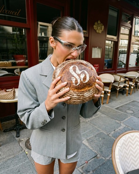 Frau vor einem Pariser Café mit einem gebrandeten Brotlaib