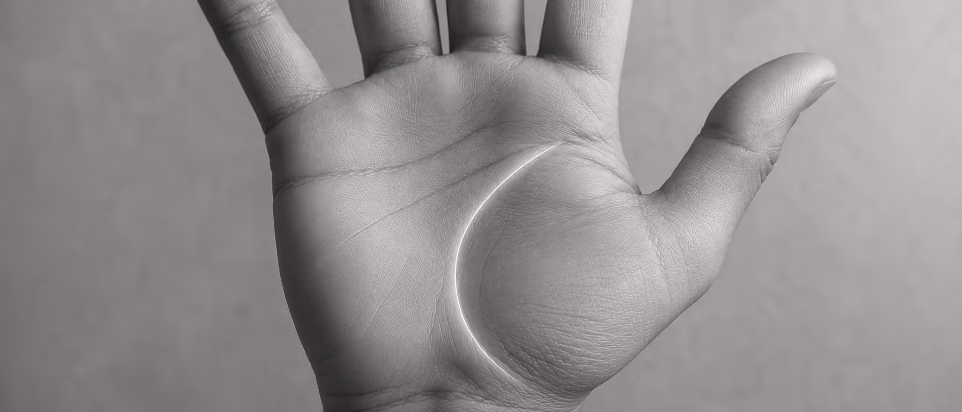 Close-up of a human palm in grayscale with a bright curved line following a crevice.